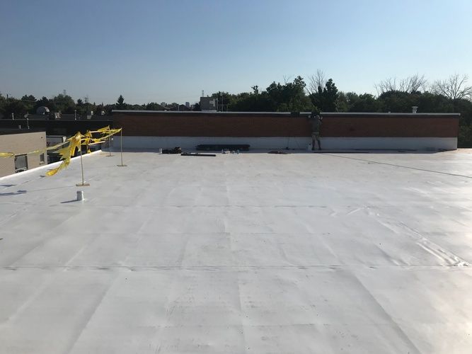 The roof of a building with a white roof and yellow flags on it.