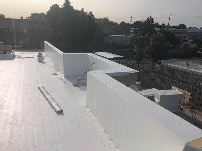 A white roof with a railing and trees in the background