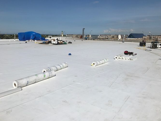 A white roof with rolls of roofing material on it.