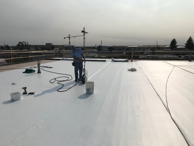 A man is painting a white roof with a roller.