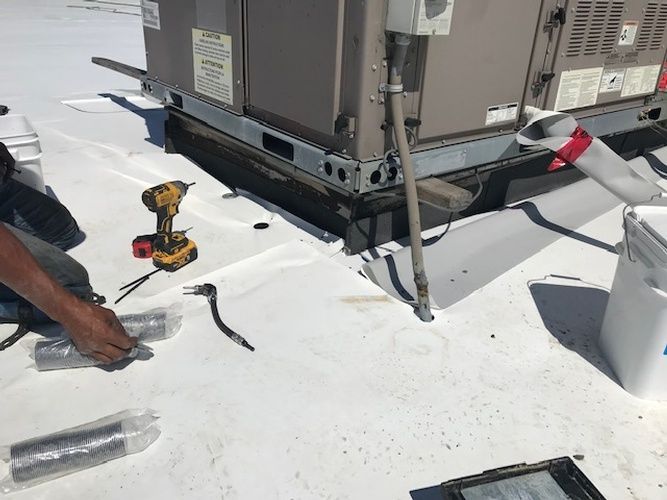 A man is working on a roof with a drill.
