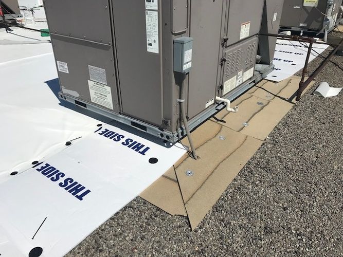 A large air conditioner is sitting on top of a white roof.