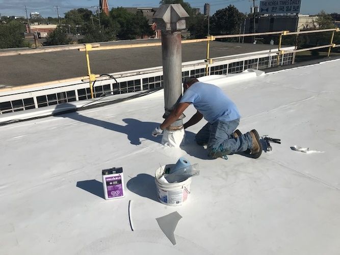 A man is kneeling on the roof of a building.