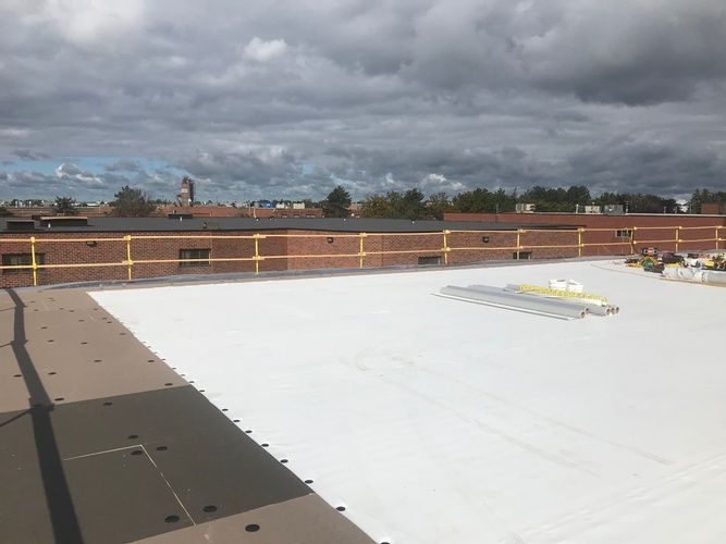 A white roof is being installed on top of a brick building.