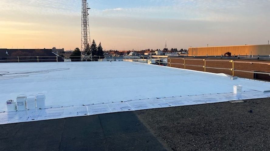 A large white roof with a crane in the background.