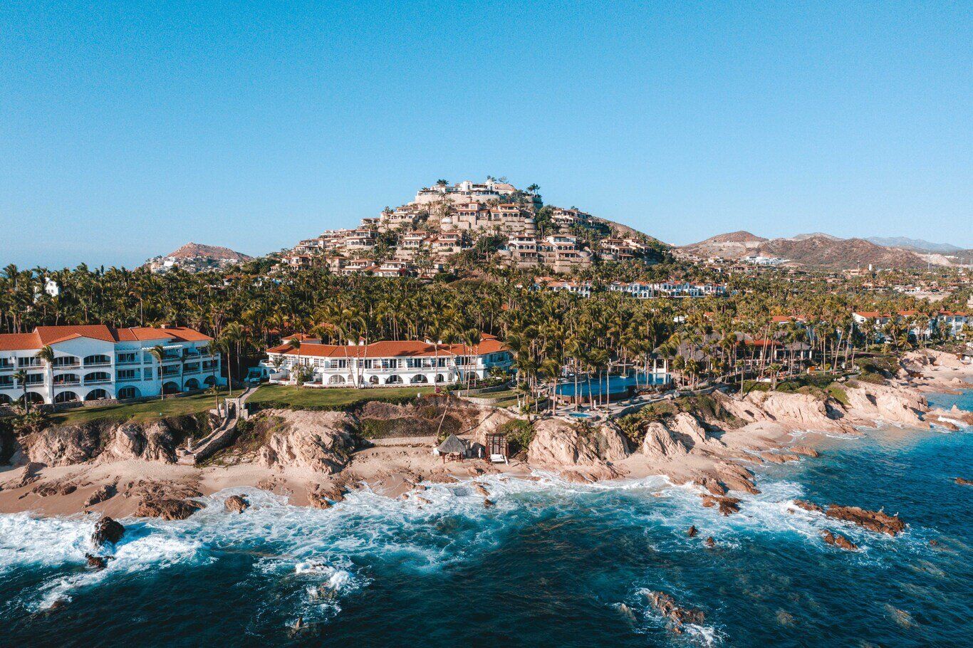 An aerial view of a resort on a hill overlooking the ocean.