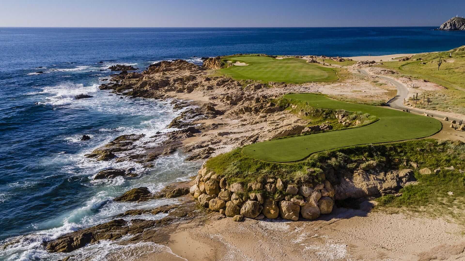 An aerial view of a golf course on a cliff overlooking the ocean.