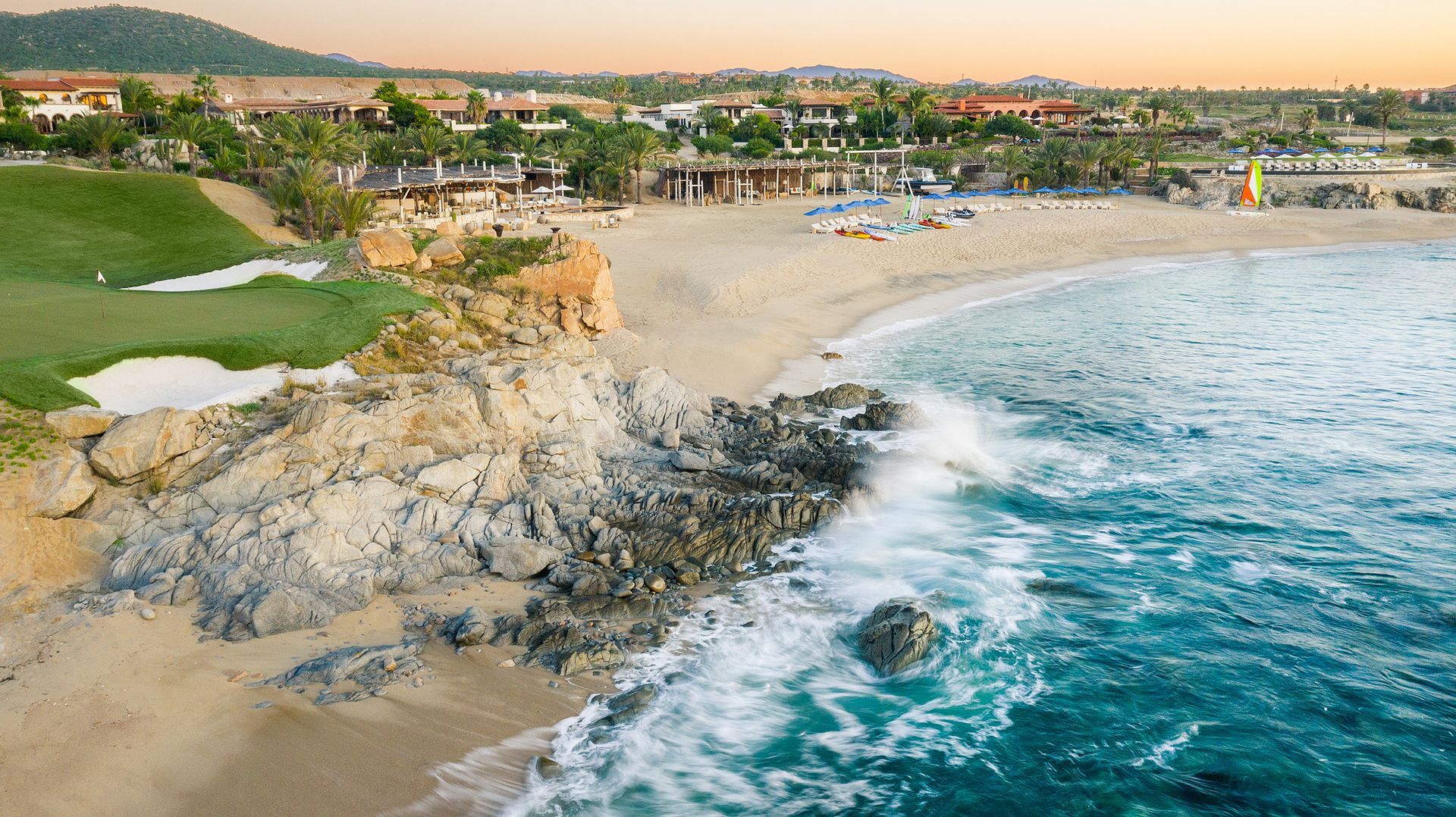 An aerial view of a beach with a golf course in the background.