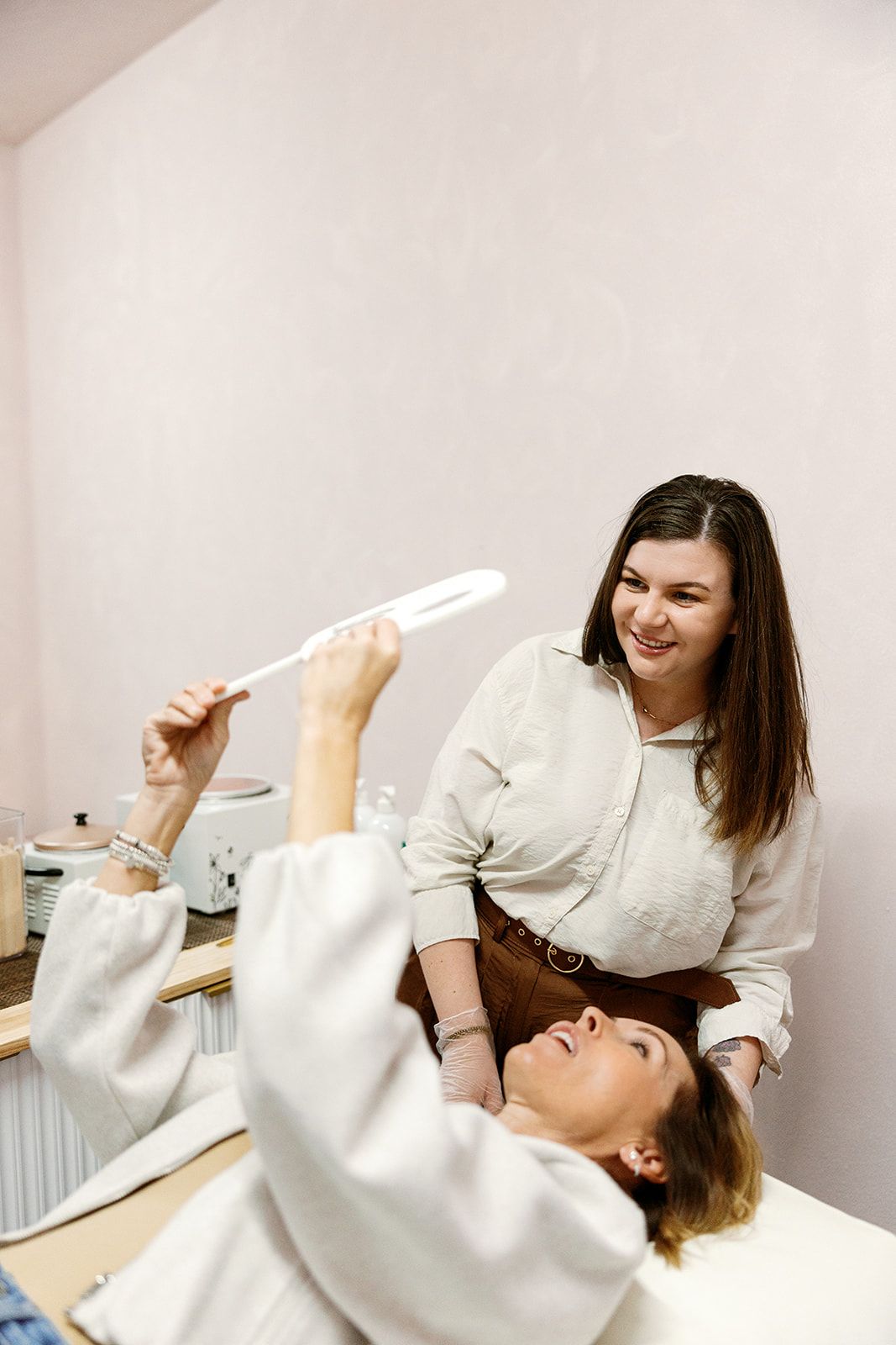 Woman with fair skin, hands near her neck, looking up, soft focus.