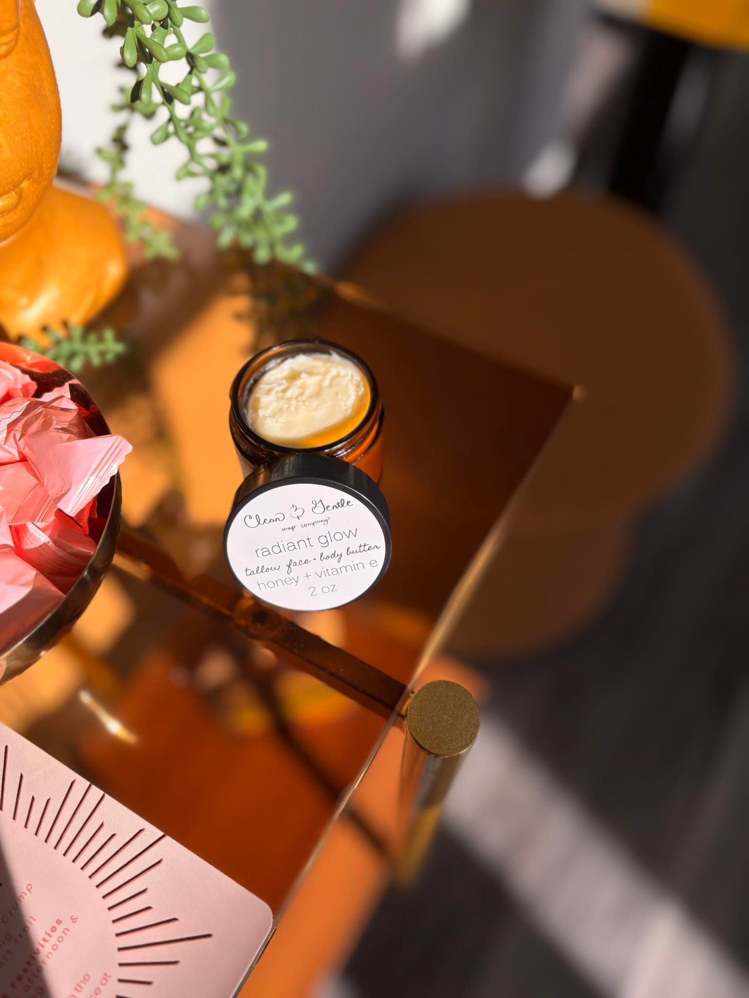 Open jar of skincare product on orange table, lid beside it.