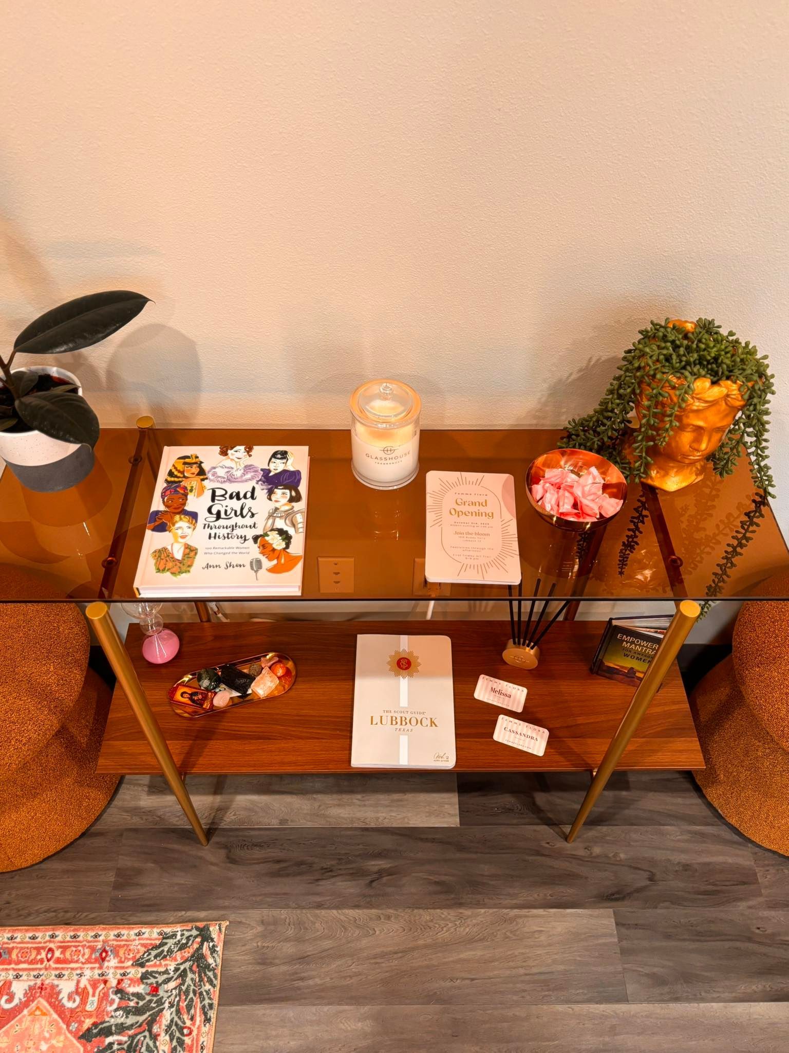 A console table with decorations including books, candles, a gift box, and plants.