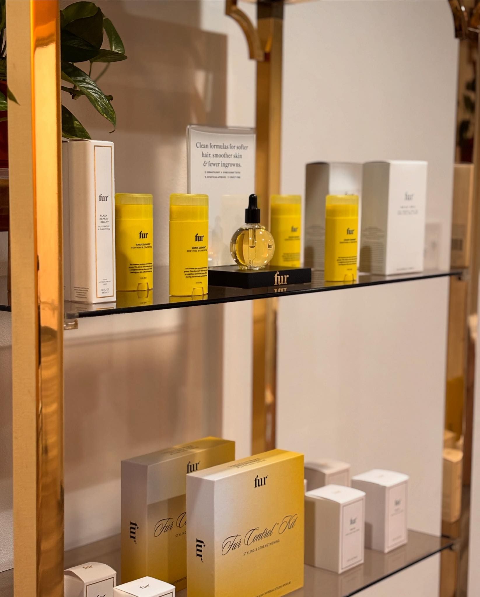 Shelf with skincare products, yellow and white packaging, gold metal frame.