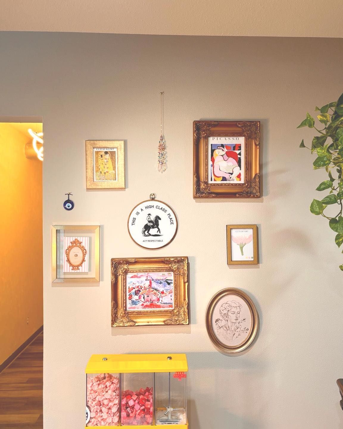 Gallery wall with ornate gold frames, featuring art and a small display case with candy.