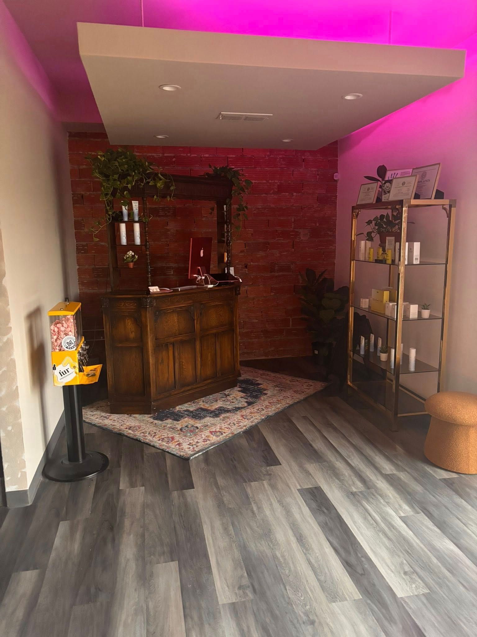 Salon reception area with a rustic wooden counter, products on shelves, and exposed brick wall.