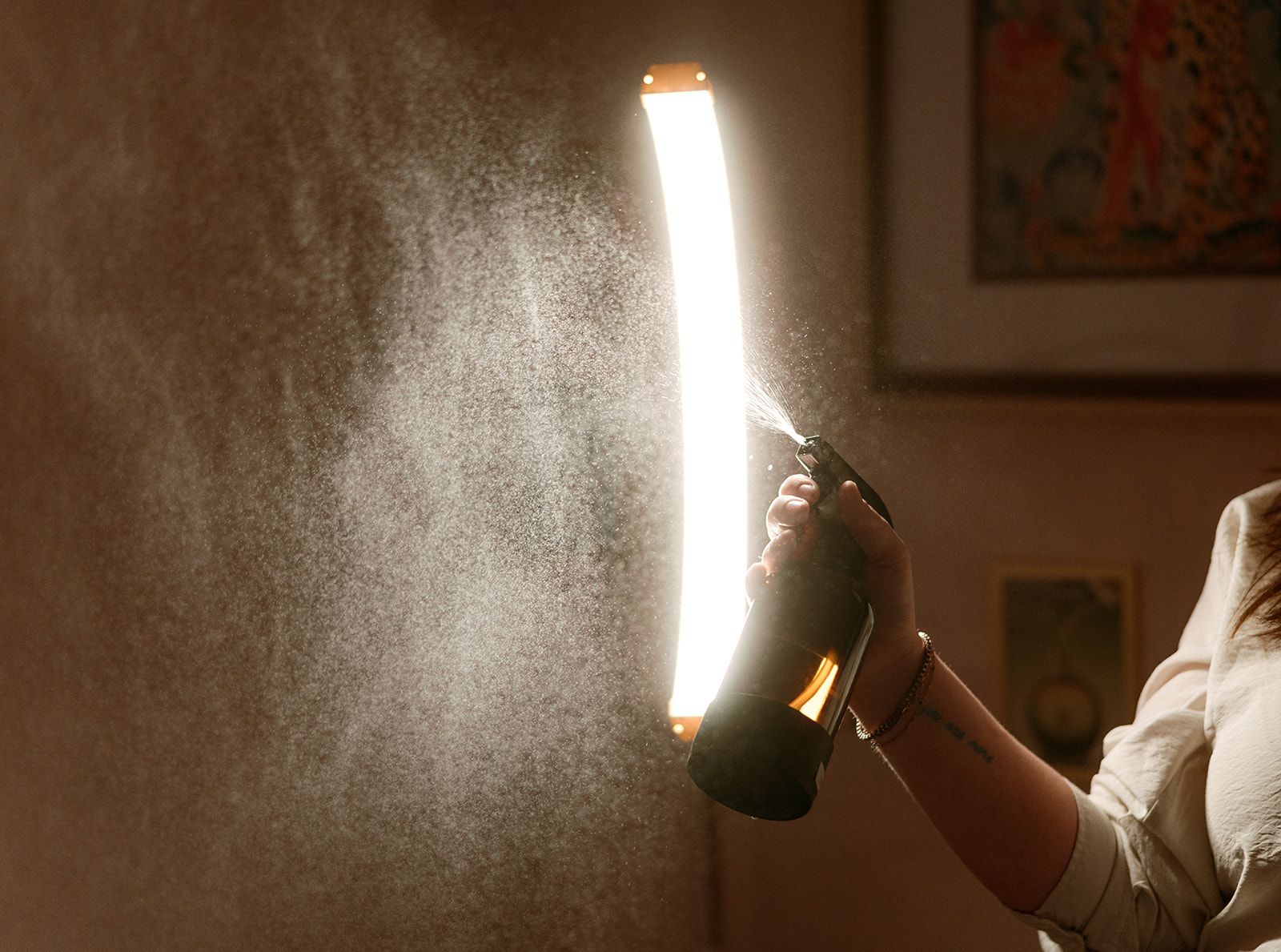 A brown soap dispenser with a label, next to a yellow rose-shaped soap and lemons on pink.