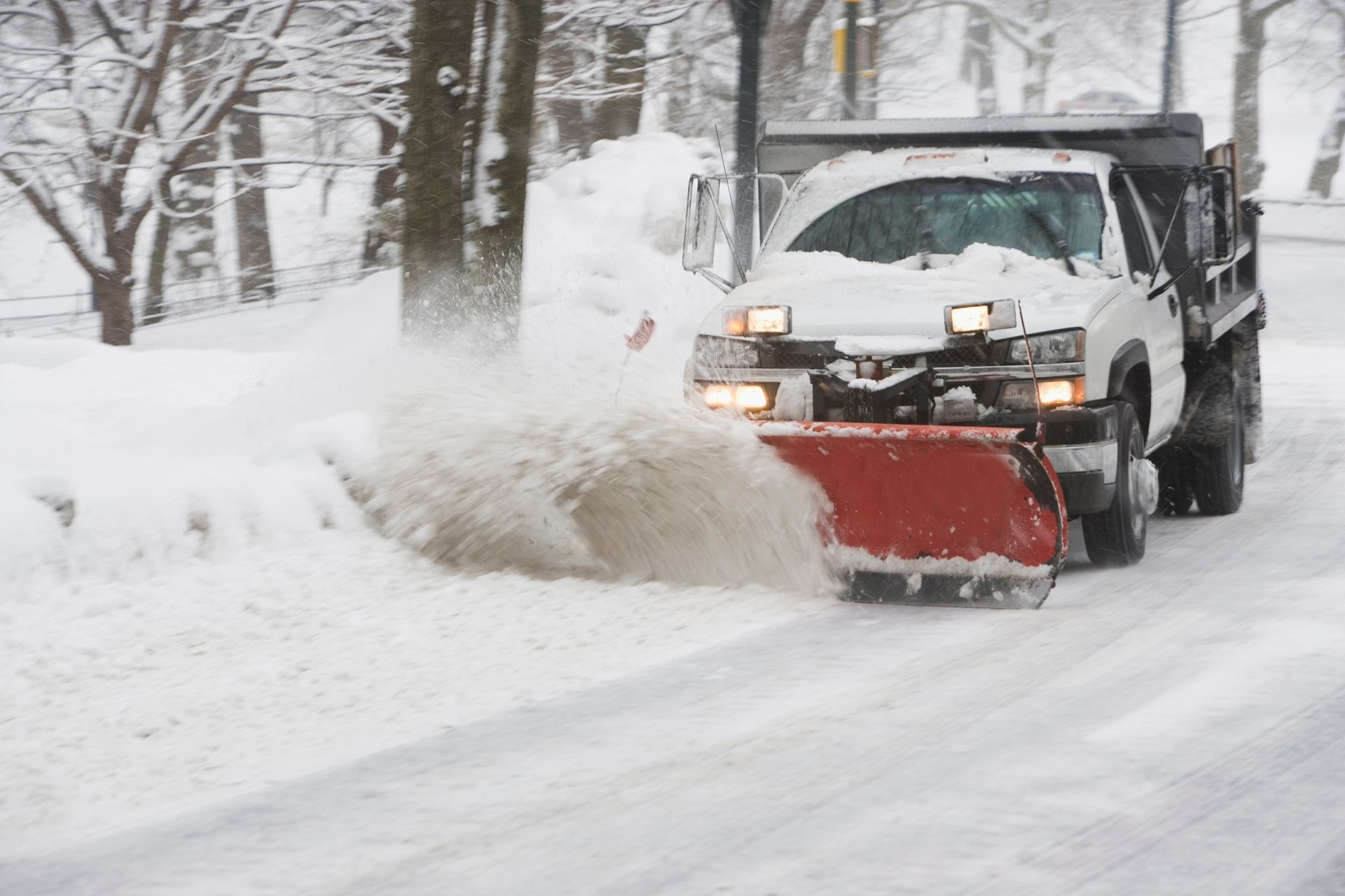 Snowplow clearing snow from a street on a snowy day.