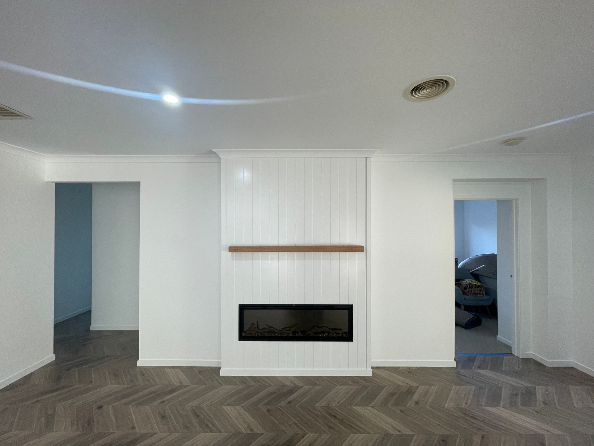 A man is painting a wall in a room with a roller.