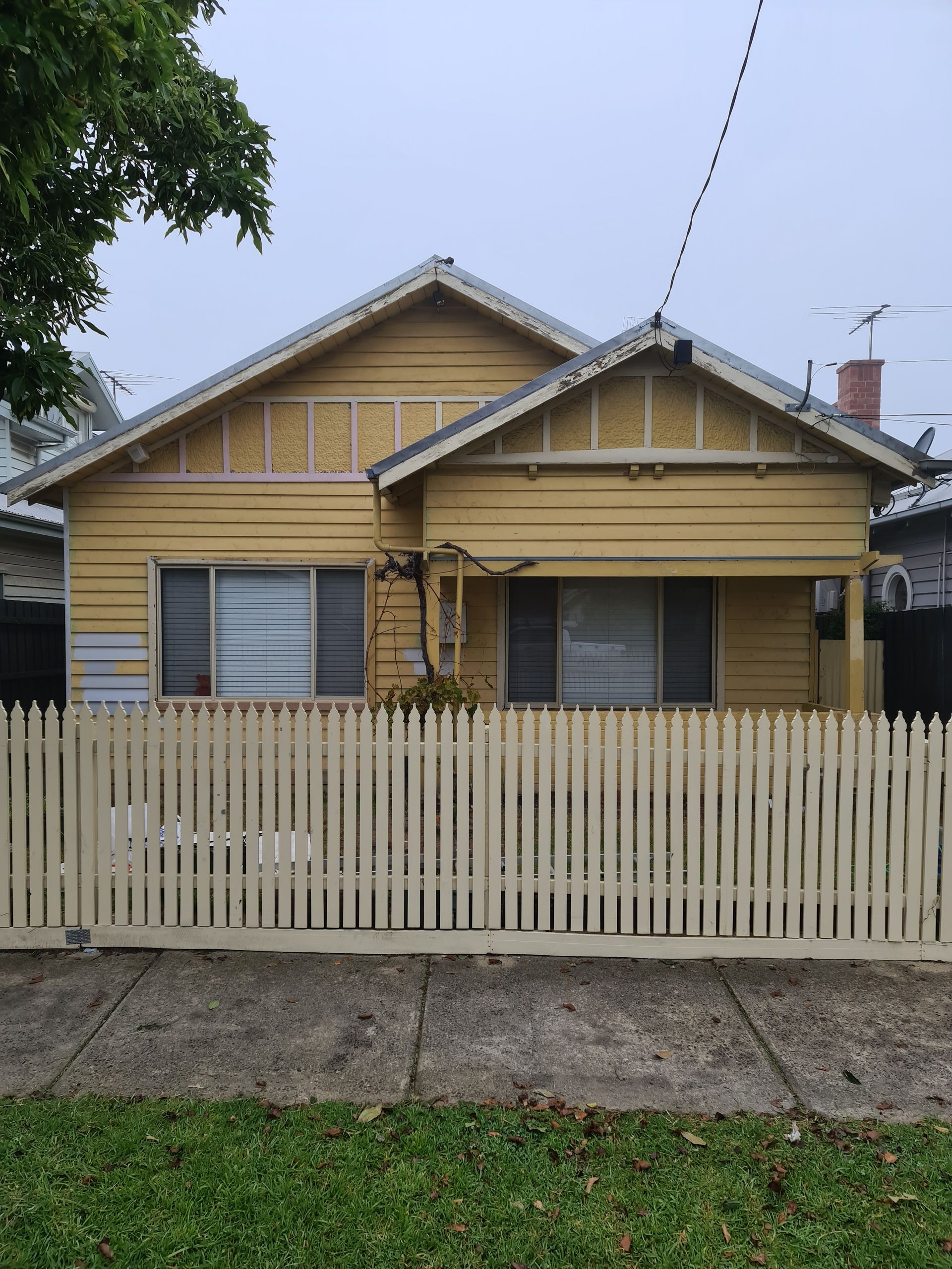 A yellow house with a white picket fence in front of it