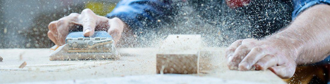 man sanding down wooden table