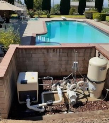 Pool equipment, including a pump and heater, in a brick enclosure next to a turquoise pool.