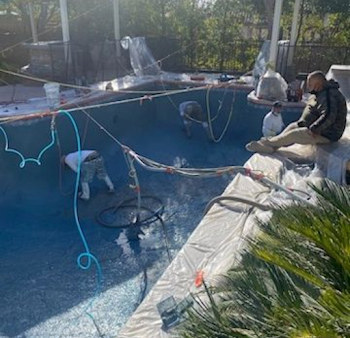 Workers resurfacing a blue-tiled swimming pool