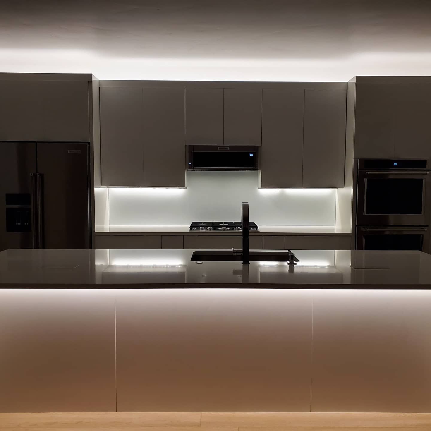 Modern kitchen with gray cabinets, island, and LED strip lighting.