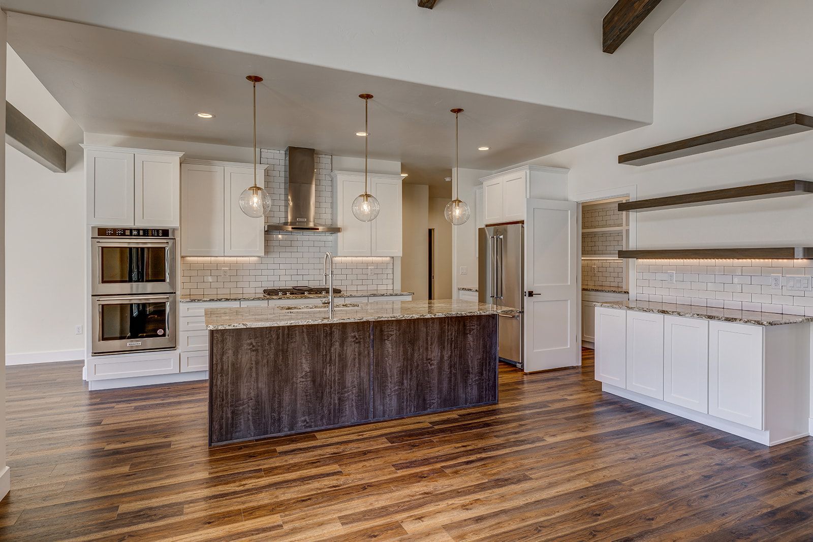 Modern kitchen with white cabinets, dark wood island, stainless steel appliances, and wood floors.