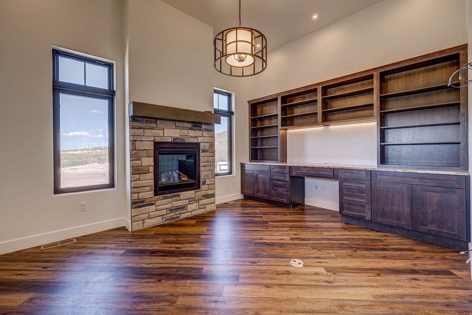 Spacious home office with fireplace, dark wood built-in shelves, and hardwood floors.