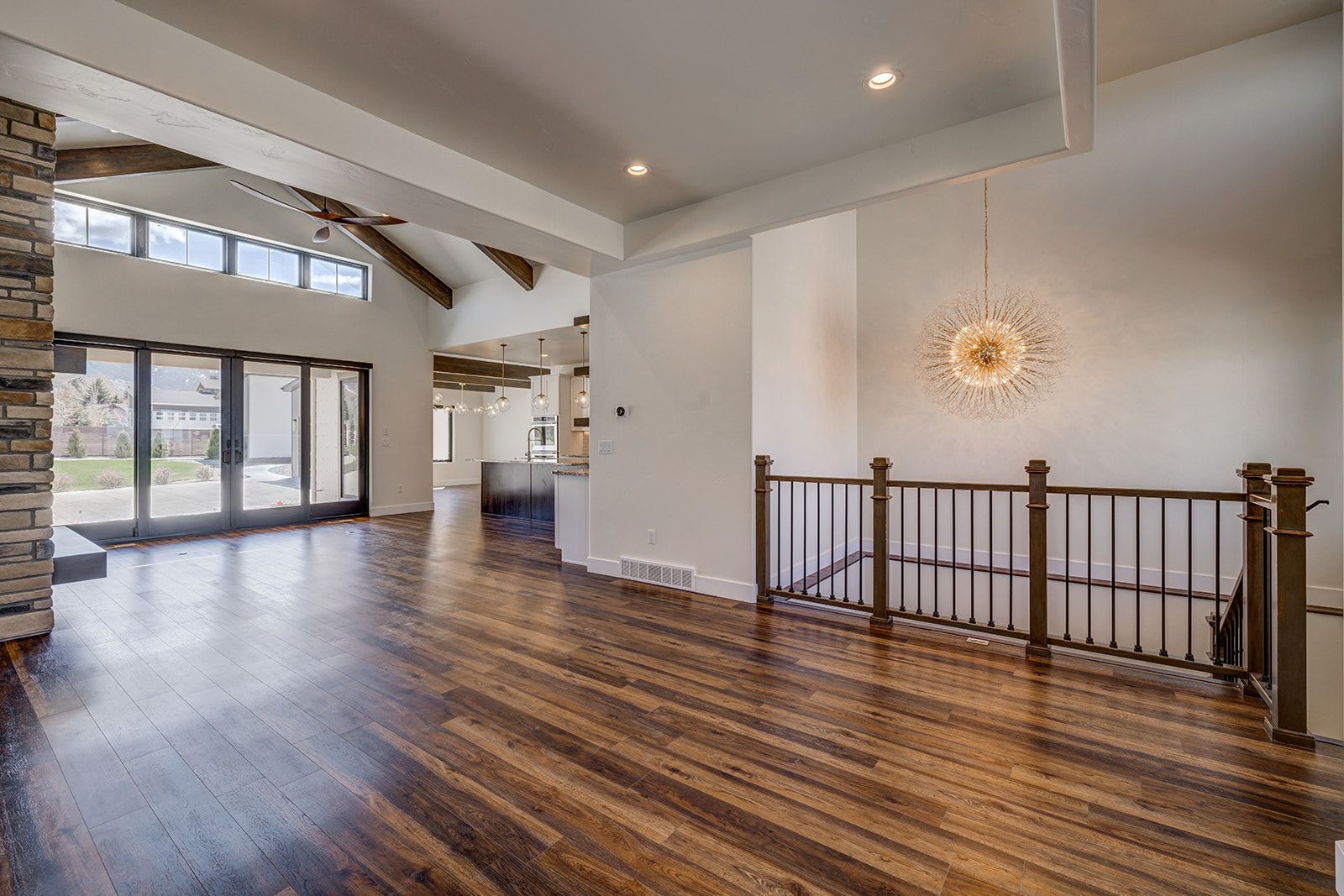 Spacious living room with hardwood floors, high ceilings, large windows, and a staircase.