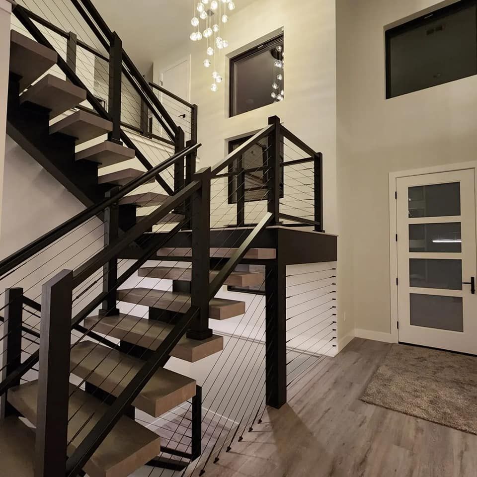 Modern staircase with black railing, light wood steps, and cable banisters.
