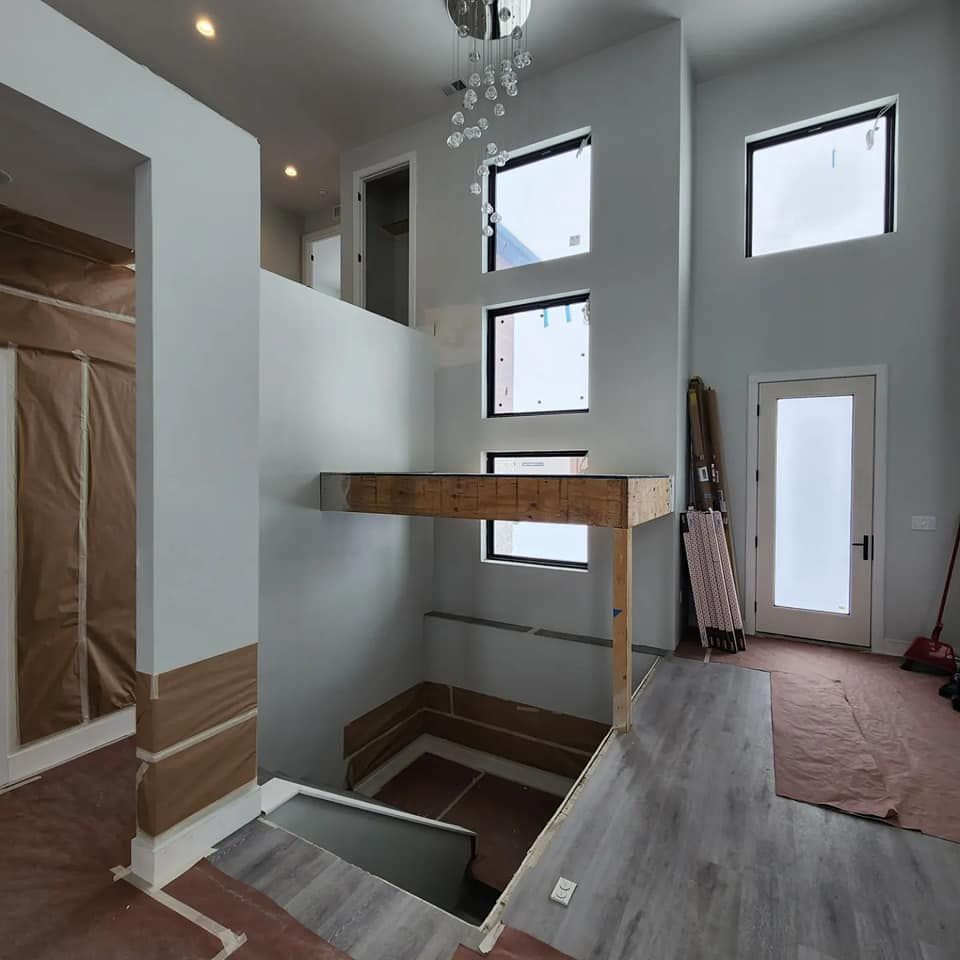 Interior view of a modern home under construction; neutral colors, multiple windows, stairs, and a partial second level.
