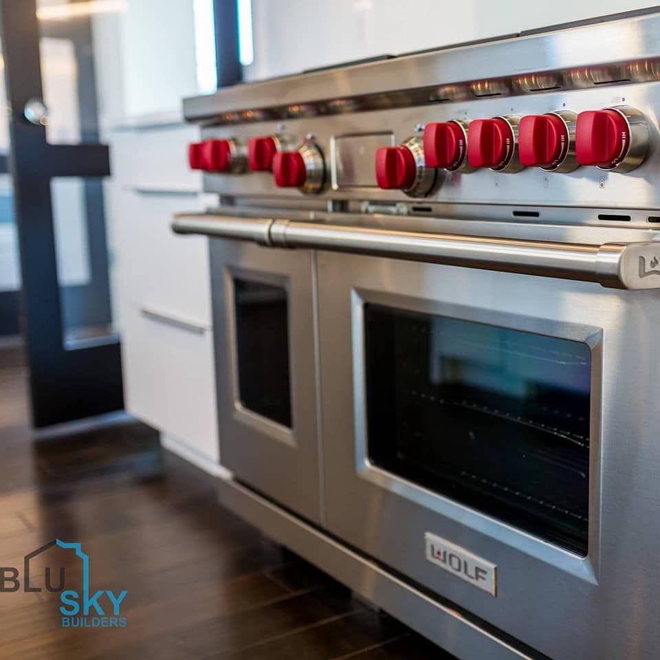 Stainless steel Wolf range with red knobs in a modern kitchen.