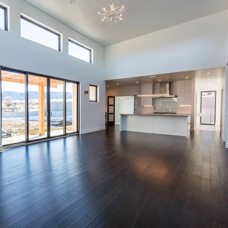 Open-concept living space with dark wood floors, large windows, and a modern kitchen.