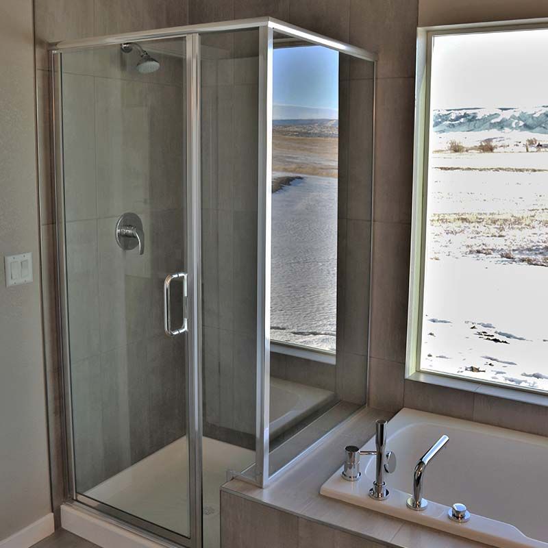 Shower with glass door, adjacent to a bathtub and window with outdoor view.