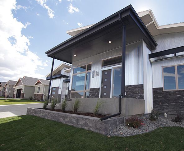 Modern home with corrugated metal siding, large windows, and dark trim; sunny day.