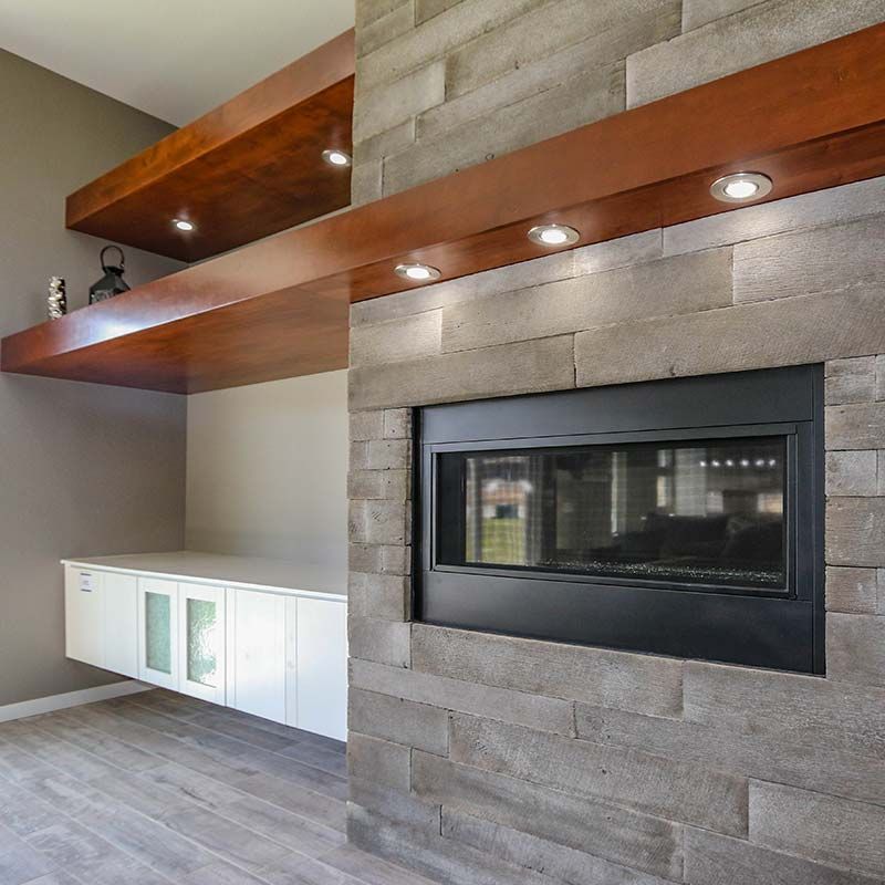 Fireplace with gray stone surround, dark metal firebox, built-in shelves, and white cabinets.