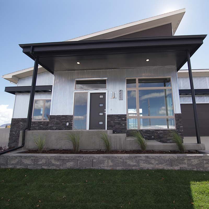 Modern home exterior with corrugated metal siding, black trim, and large windows.