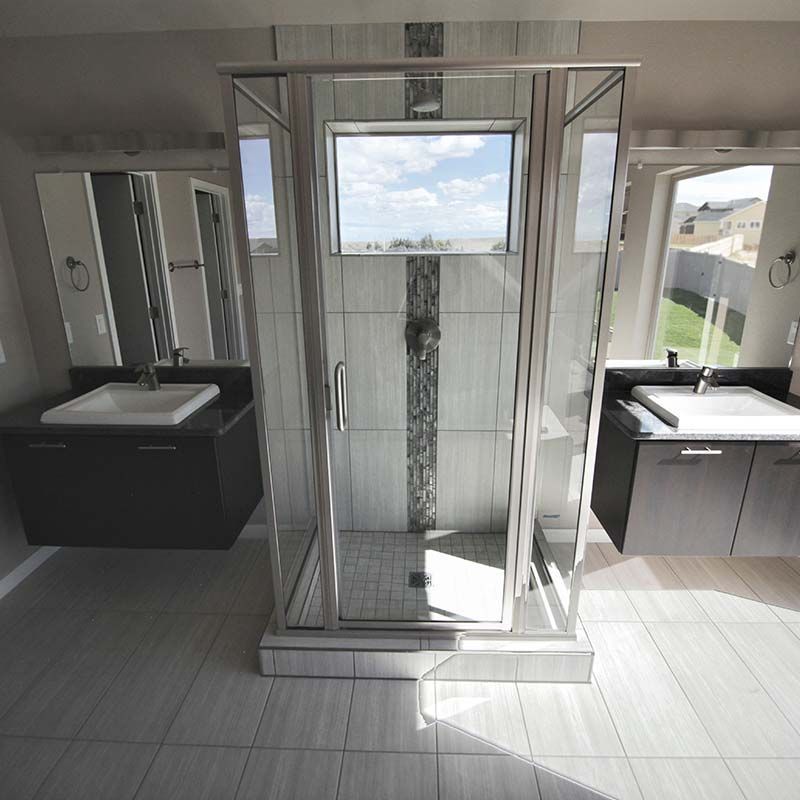 Modern bathroom with a glass shower, two sinks, and a window with a view.