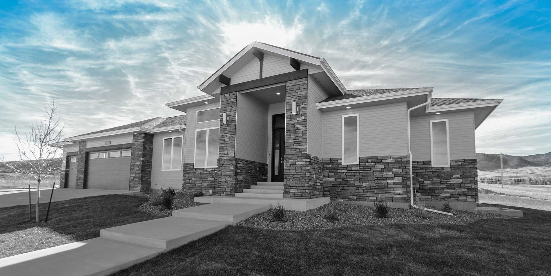 Modern house with stone accents, blue sky.