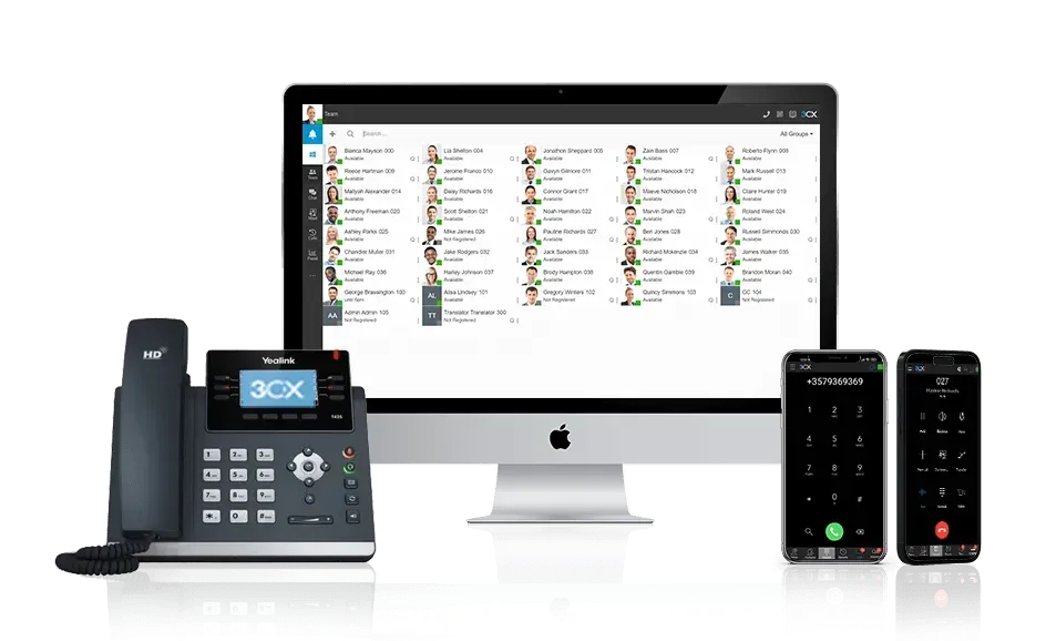 A computer monitor , a telephone , and two phones are sitting next to each other.