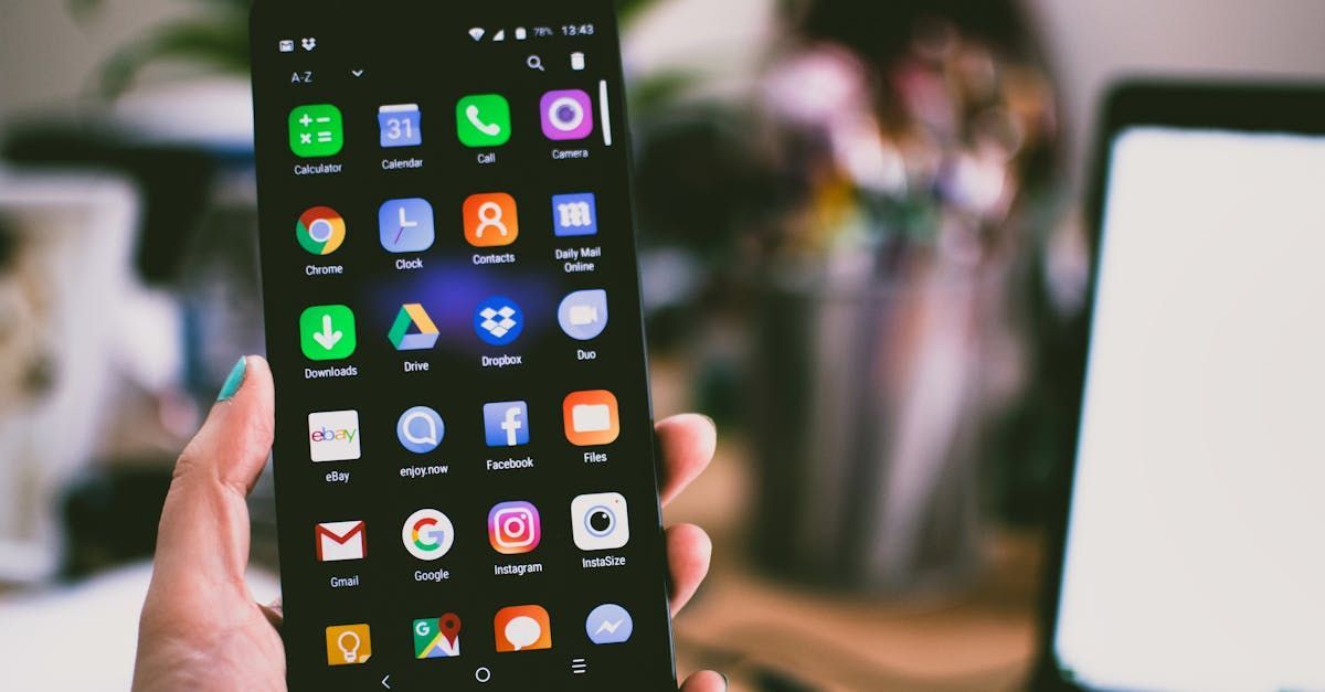 A person is holding a cell phone with a lot of apps on it.
