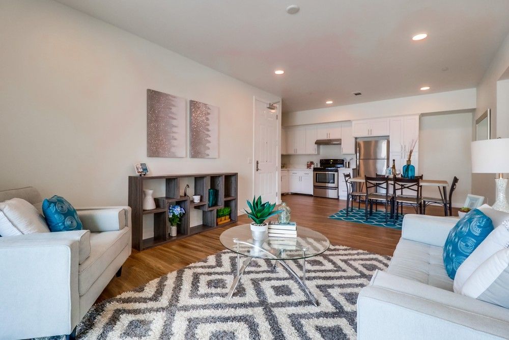 Living room with couches, rug, coffee table, and open kitchen with dining area.