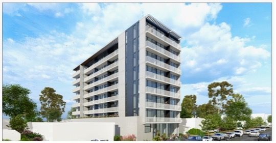 Man in a suit smiling broadly at the camera; blue patterned tie.