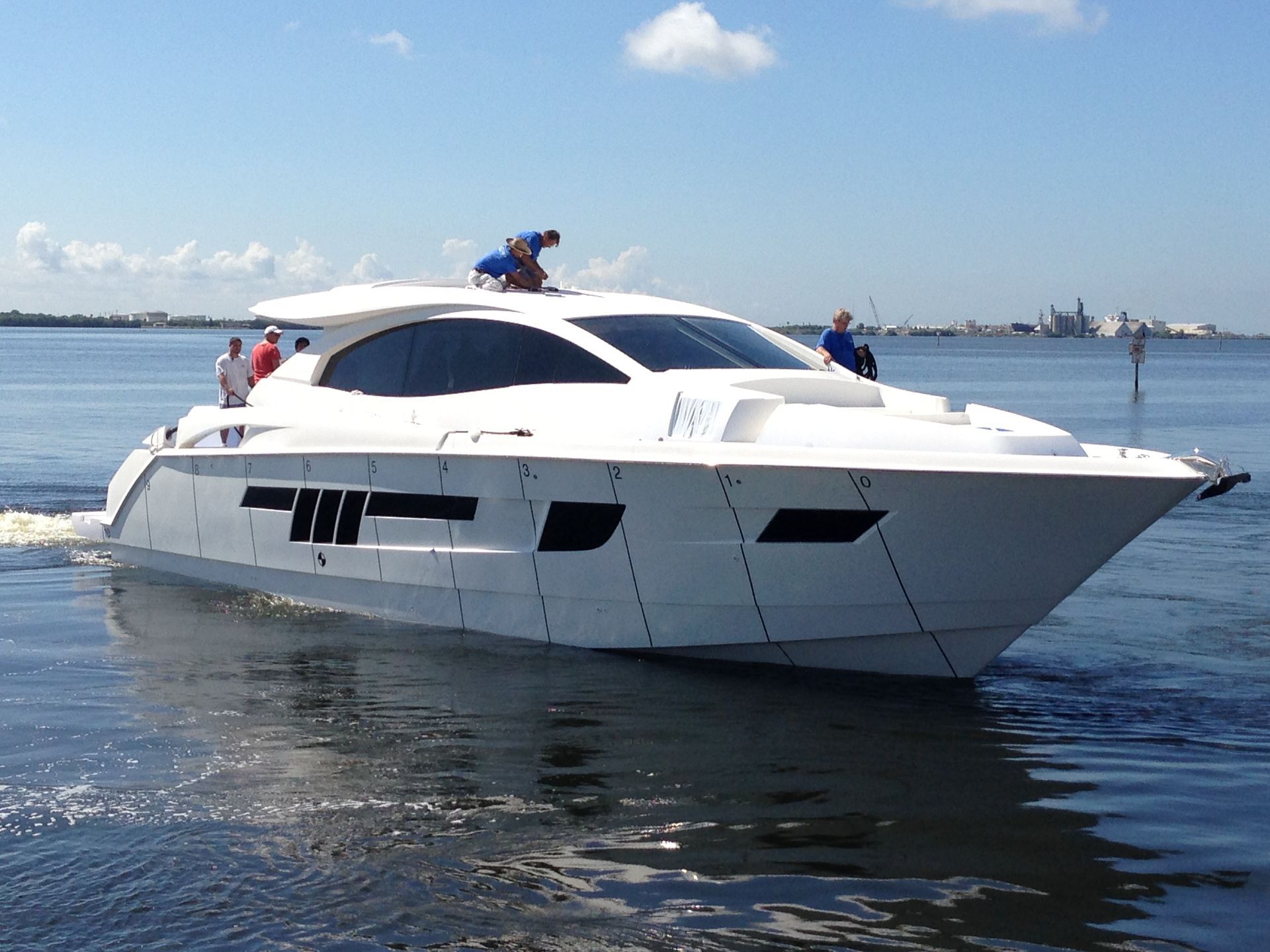 White motor yacht on water, with people on deck, under a sunny sky.
