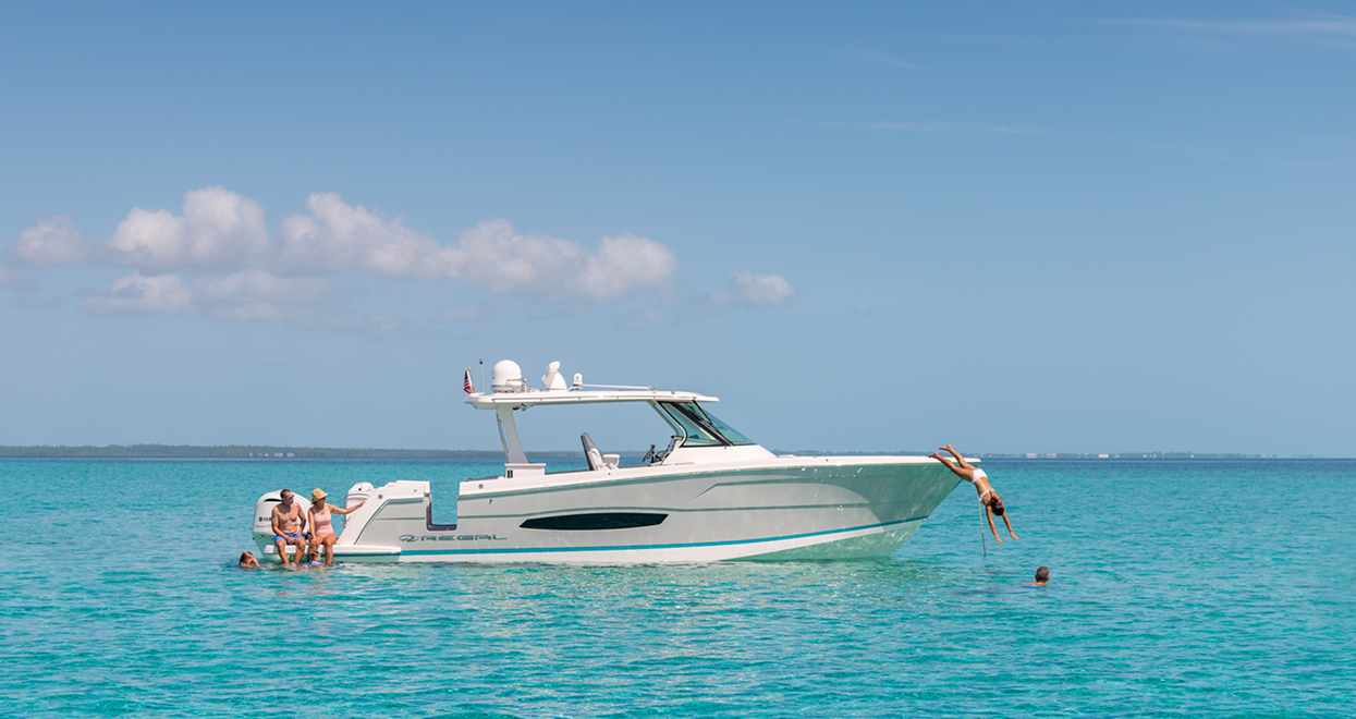 Boat in turquoise water with people swimming and relaxing.