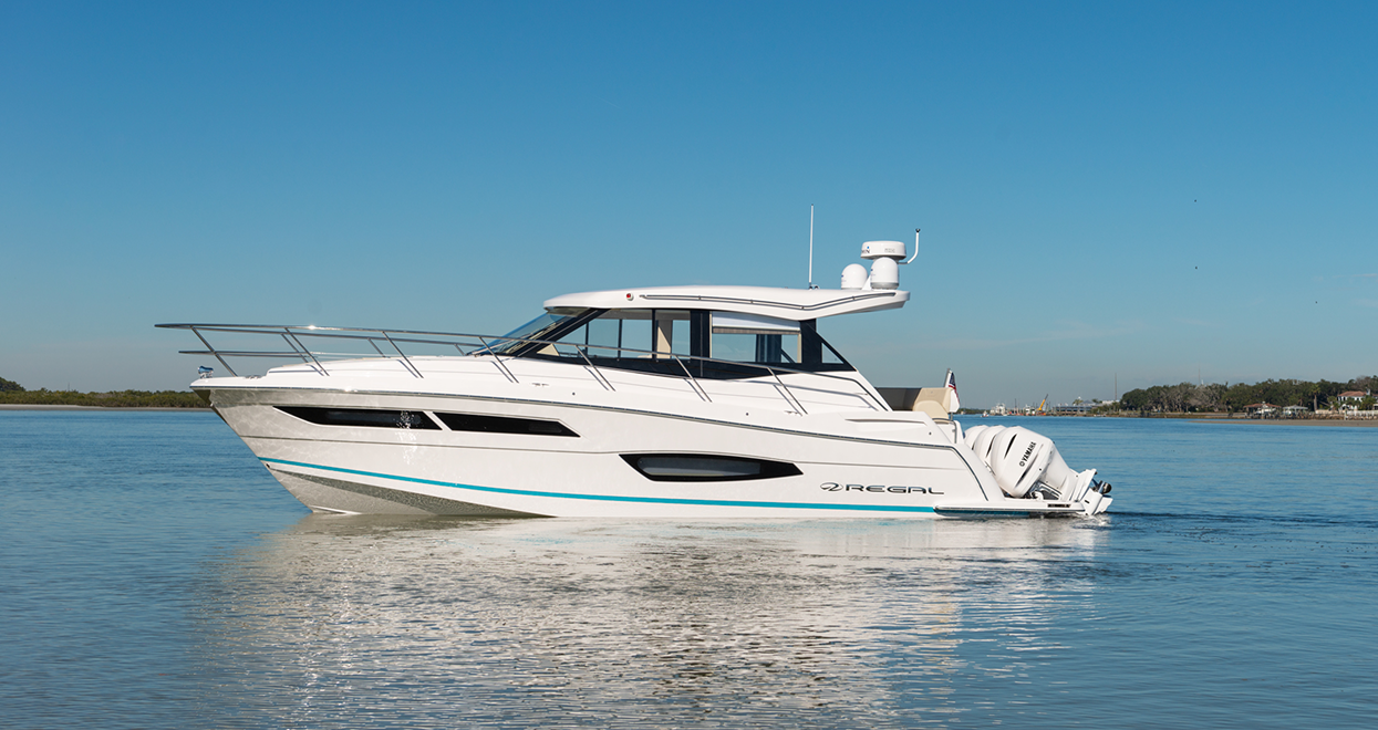 White motorboat cruising on calm blue water under a clear sky.
