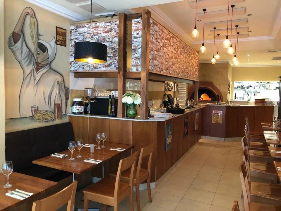 A restaurant with tables and chairs and a painting on the wall