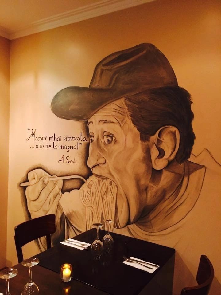 A painting of a man eating spaghetti on a wall