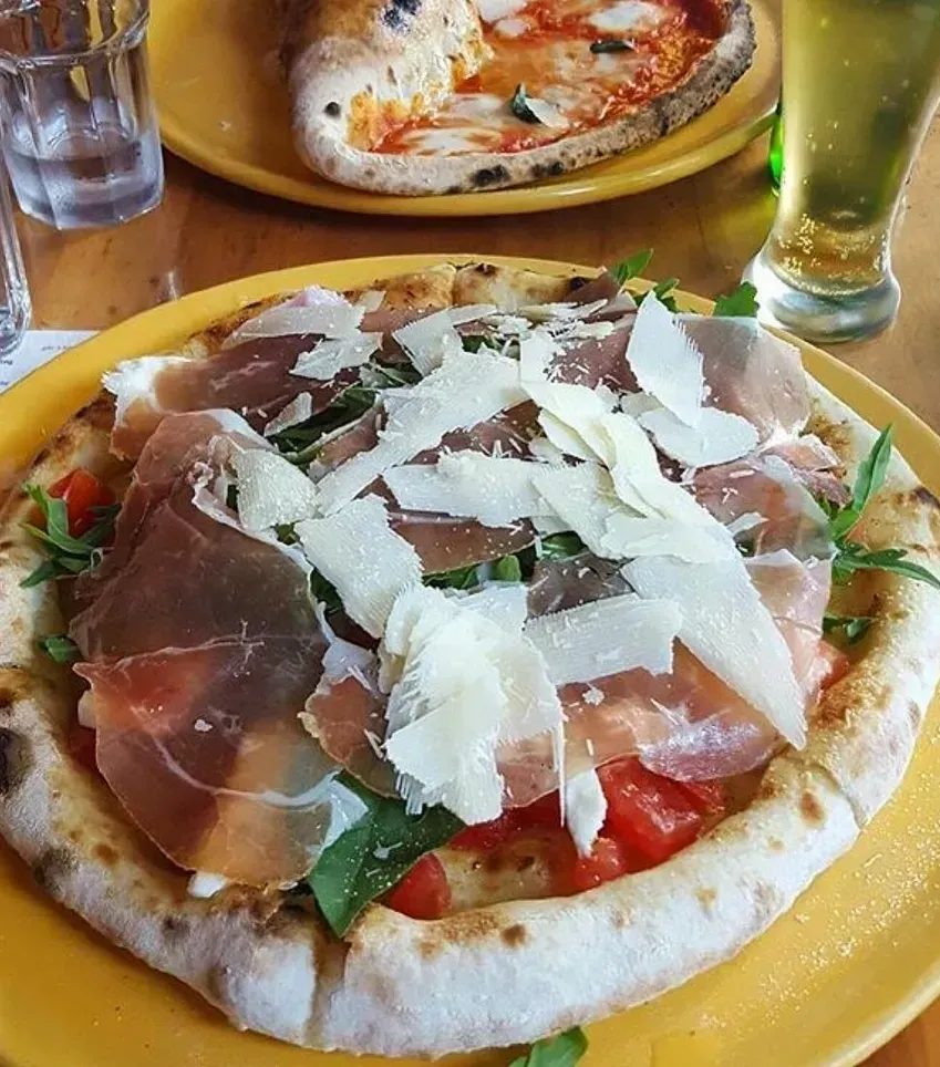 A pizza with meat and cheese on a yellow plate