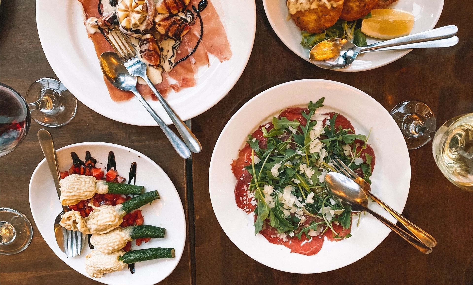 A table topped with plates of food and wine glasses.